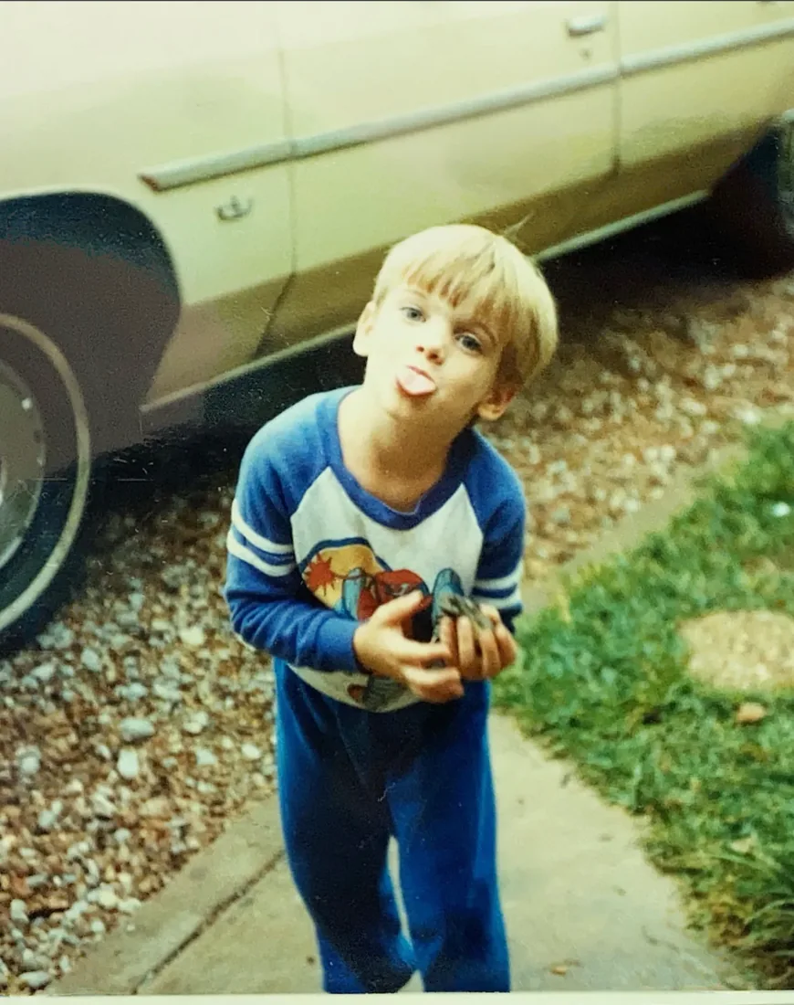 A childhood photo of a boy holding a baseball glove