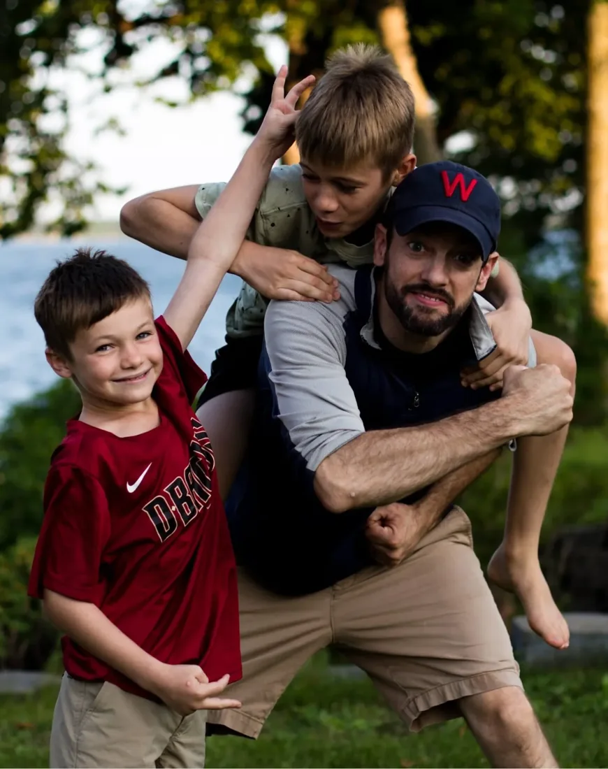 Eric with two children outdoors, one riding on his shoulders